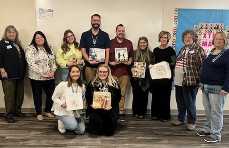 Six, 5th grade teachers. the principal and vice principal of Mead elementary, and three members of the Carbon Valley DAR chapter are shown holding some of the books and a book bag donated thanks to the Freedom Sack Project.