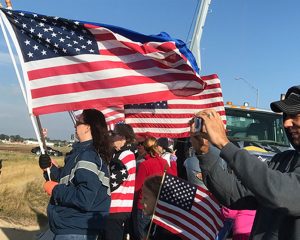 Group of Carbon Valley Chapter and SAR chapter members waving flags as a bus containing veterans travels under the bridge on the way to the airport on the honor flight.