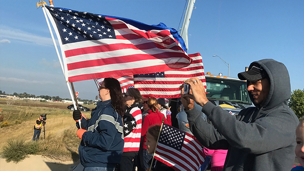 Group of Carbon Valley Chapter and SAR chapter members waving flags as a bus containing veterans travels under the bridge on the way to the airport on the honor flight.