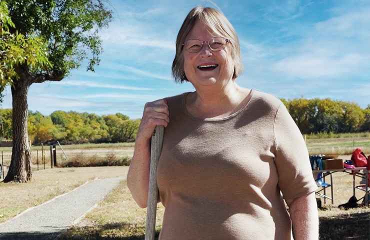 A chapter member stands by a headstone in the Highlandlake Pioneer Cemetery. Carbon Valley Chapter NSDAR helps to clean this cemetery every fall as part of the Day of Service.